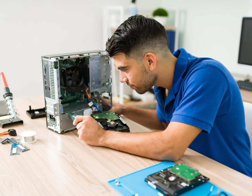 Técnico de soporte IT reparando y manteniendo computador de escritorio en oficina