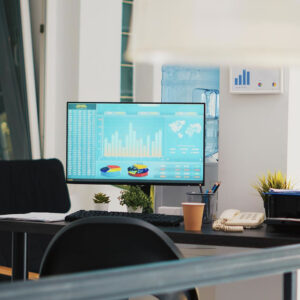 Puesto de trabajo de oficina con PC optimizada mostrando panel de datos y gráficos